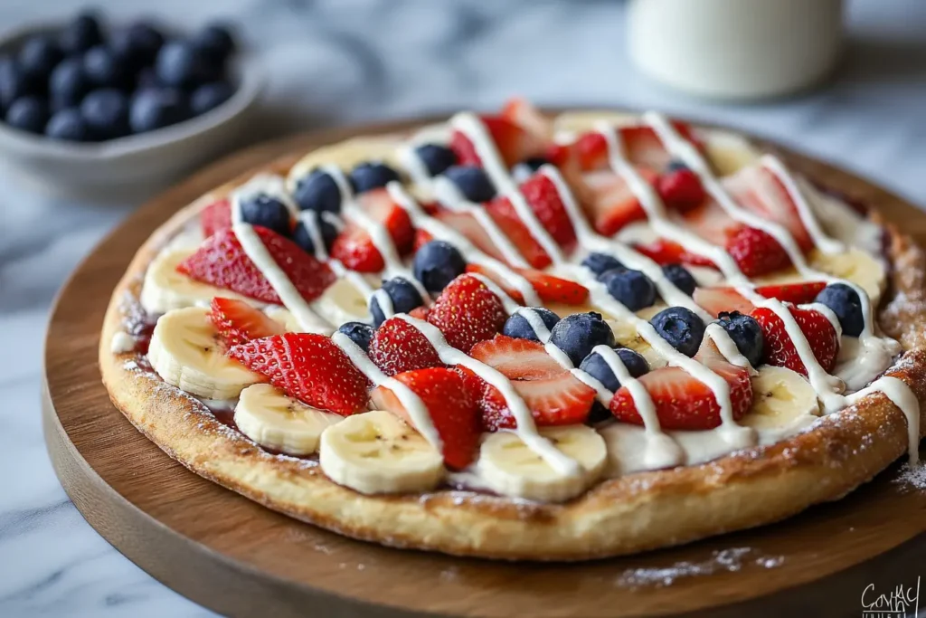 Sweet breakfast pizza with fresh strawberries, blueberries, bananas, and cream cheese frosting.